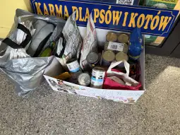 Skrzynka z darami dla psów i kotów, wypełniona puszkami i karmą.