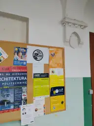 Tablica ogłoszeń z plakatami i informacjami o wydarzeniach edukacyjnych.