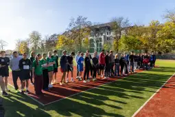 Grupa ludzi stojąca na boisku sportowym, przygotowująca się do zawodów.