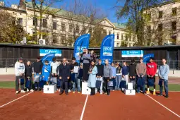 Uczestnicy zawodów sportowych na podium z nagrodami i flagami.