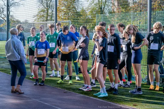Grupa młodych sportowców przygotowujących się do biegu na boisku.