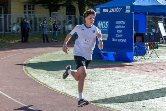 Młody biegacz na torze lekkoatletycznym podczas zawodów sportowych.