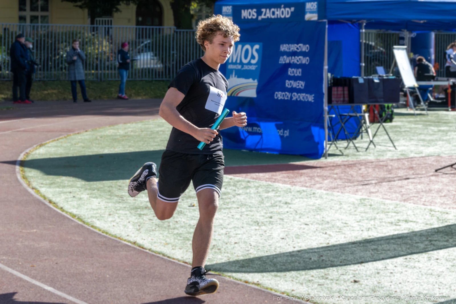 Biegacz na torze lekkoatletycznym z pałeczką w ręku.  Autor: Piotr Wojnarowski