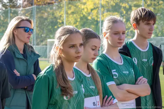 Grupa młodych sportowców w strojach drużynowych, czekających na rozpoczęcie zawodów.