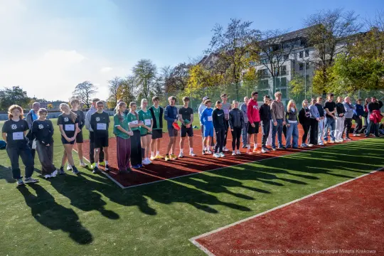 Grupa osób stojąca na boisku sportowym, przygotowująca się do zawodów.