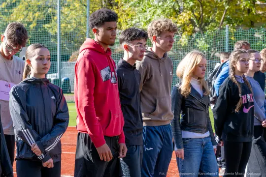 Grupa młodzieży w strojach sportowych podczas zawodów na boisku.