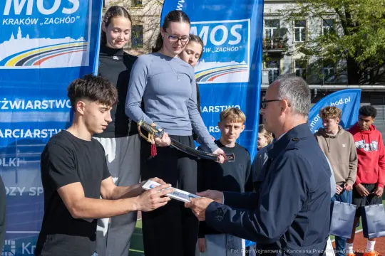 Wręczenie nagród podczas zawodów sportowych, uczestnicy na podium z dyplomami.