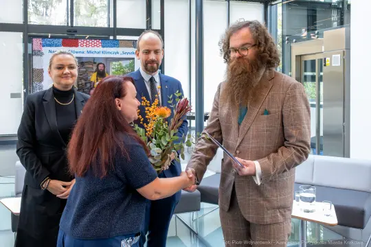 Uroczystość wręczenia nagrody z kwiatami i gratulacjami.
