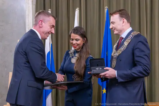 Ceremonia wręczenia odznaczeń w obecności flag i przedstawicieli władz.