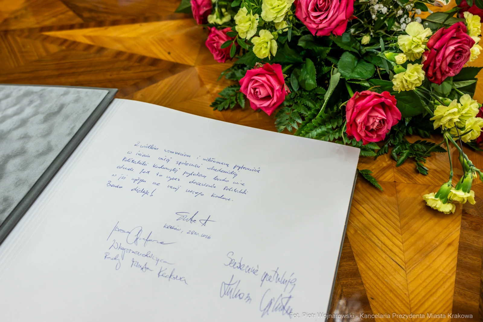 Księga pamiątkowa z podpisami i bukietem róż.  Autor: Piotr Wojnarowski