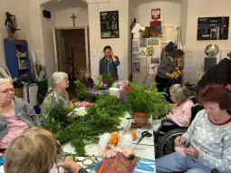 Warsztaty florystyczne z udziałem osób w różnym wieku, tworzenie kompozycji z kwiatów.