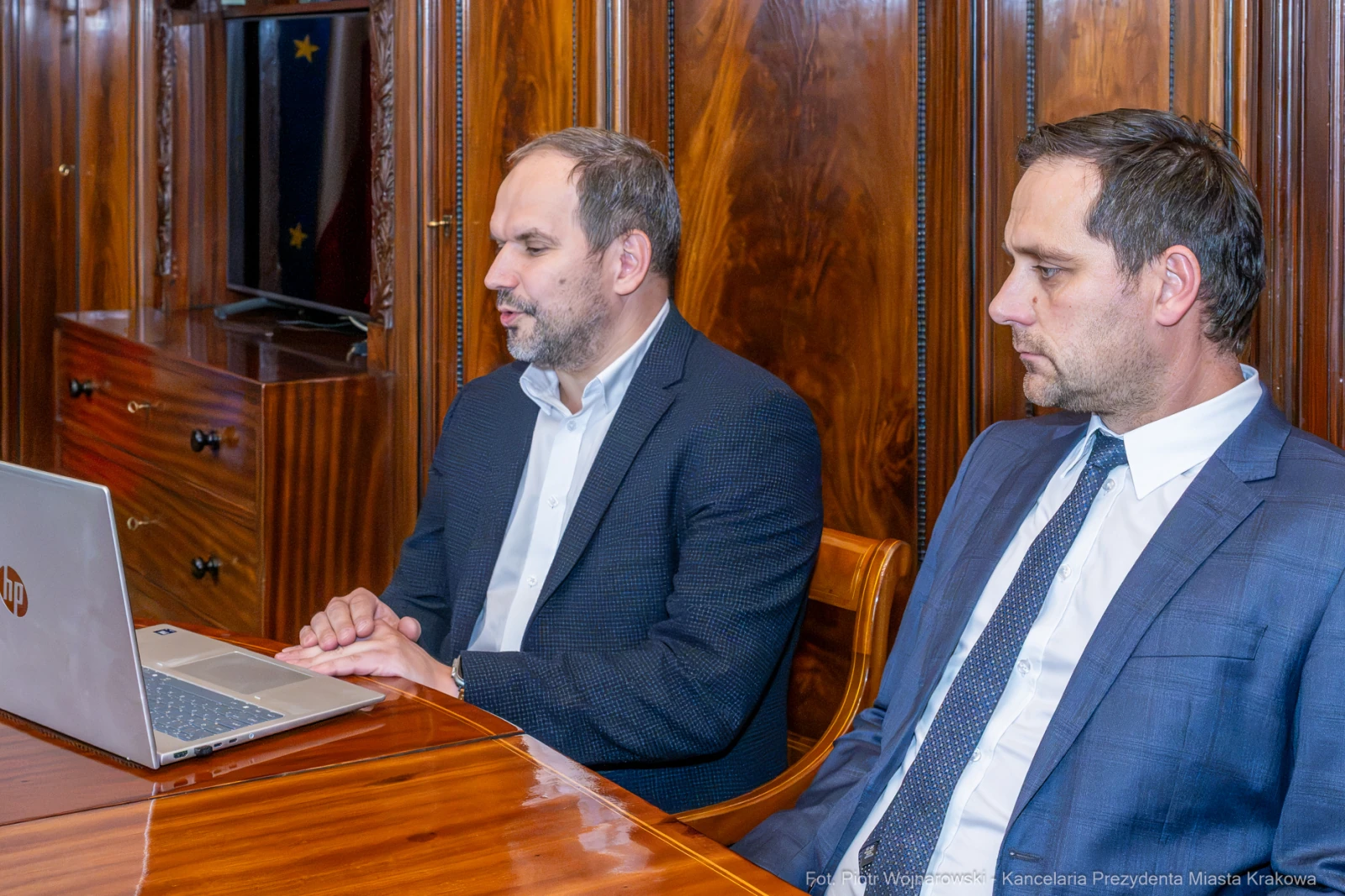 Dwóch mężczyzn siedzących przy stole, jeden z laptopem, w tle drewniana ściana.  Autor: Piotr Wojnarowski