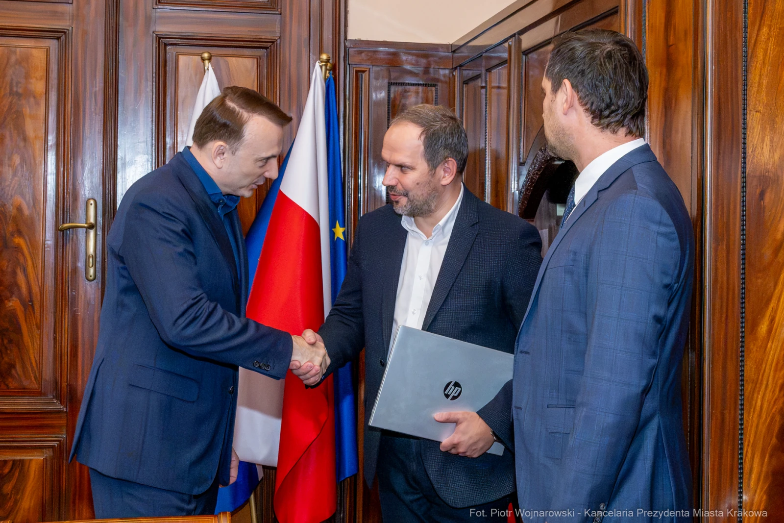 Spotkanie dwóch mężczyzn, uściski dłoni, flagi Polski i Unii Europejskiej w tle.  Autor: Piotr Wojnarowski