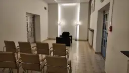 Pusty pokój z krzesłami, stołem i świecznikami.