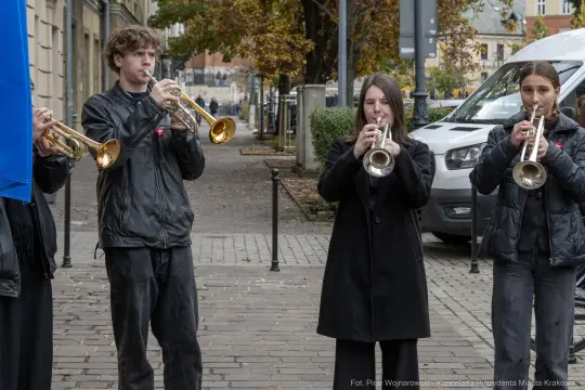 Czwórka młodych muzyków grających na trąbkach na ulicy.