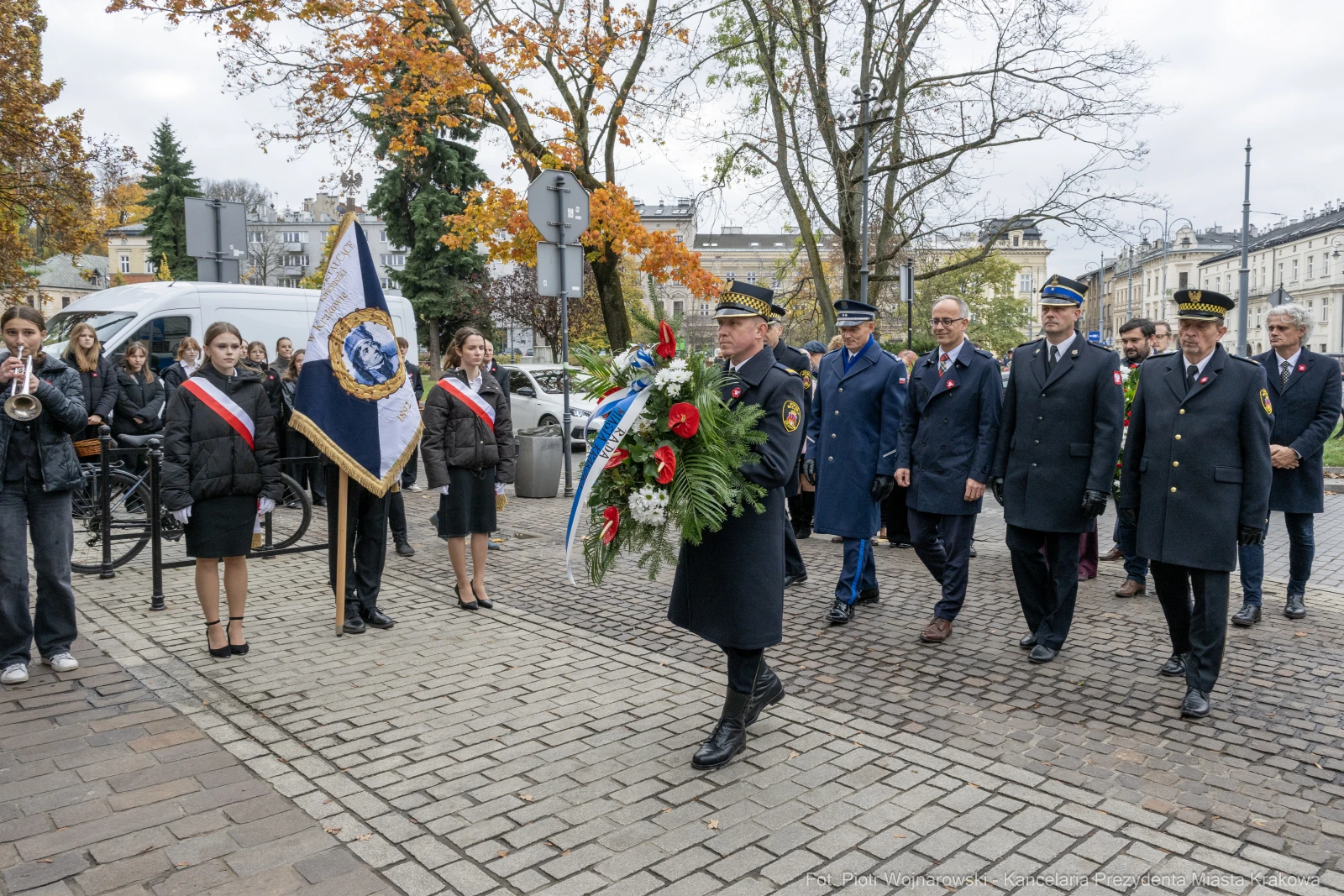Uroczystość złożenia wieńca przez delegację w mundurach, z flagą i uczestnikami w strojach formalnych.  Autor: Piotr Wojnarowski