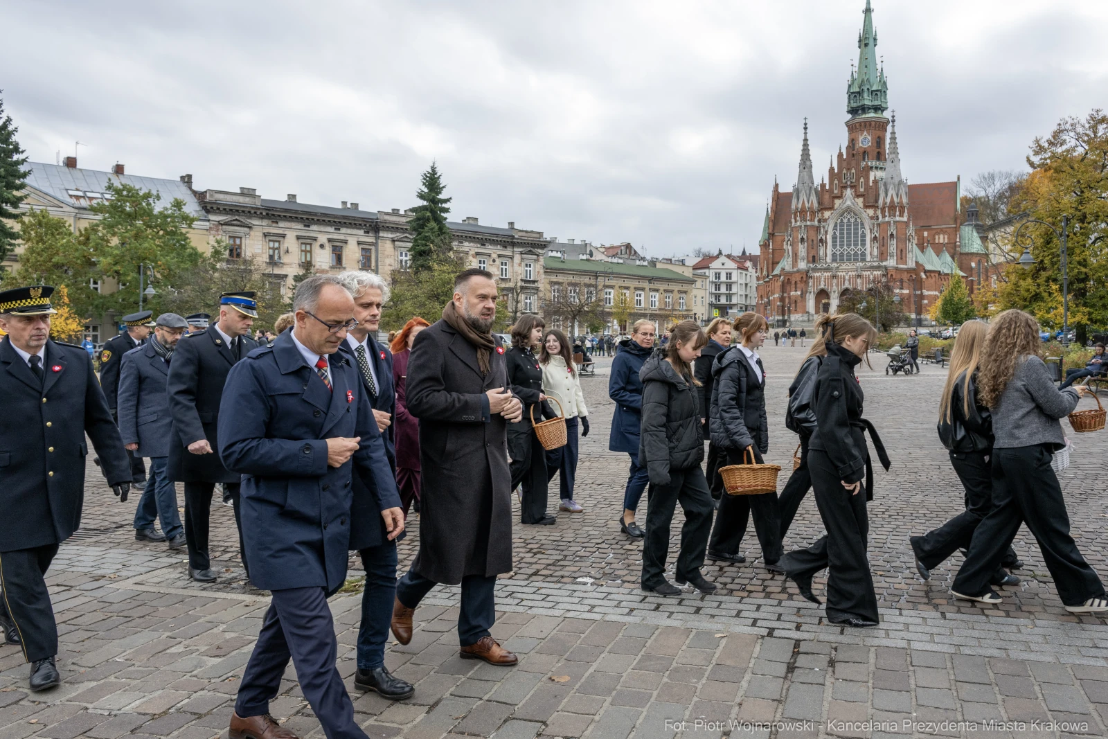 Uczestnicy ceremonii z koszykami w rękach na tle zabytkowej architektury.  Autor: Piotr Wojnarowski
