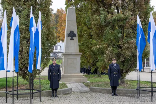 Pomnik z flagami, dwaj żołnierze w mundurach stojący na straży.
