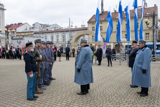Uroczystość wojskowa z żołnierzami w mundurach i flagami.