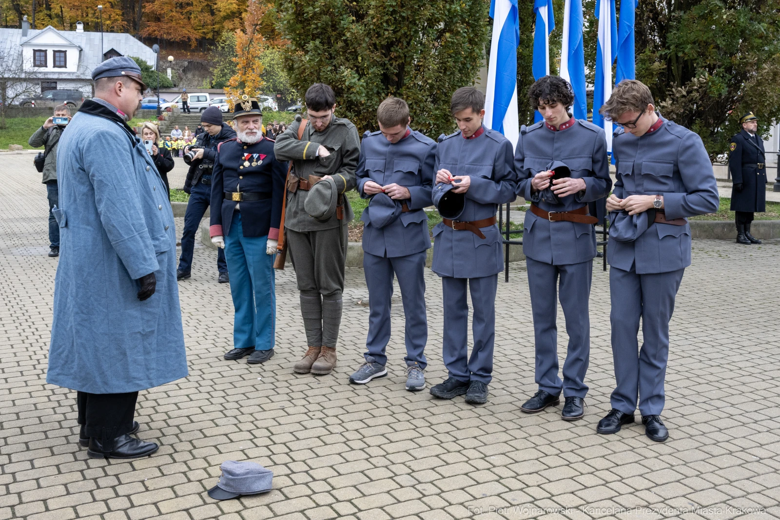 Grupa mężczyzn w historycznych mundurach podczas ceremonii, jeden z nich w szarym płaszczu.  Autor: Piotr Wojnarowski