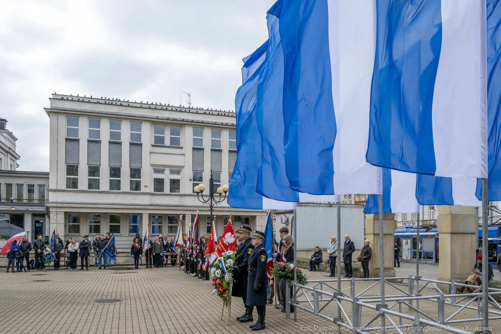 Uroczystość z flagami i pocztami sztandarowymi w miejskim otoczeniu.  Autor: Piotr Wojnarowski