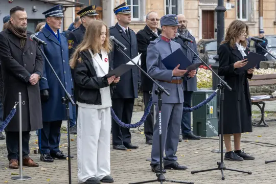 Ceremonia z udziałem osób w mundurach i przemawiających przy mikrofonach.