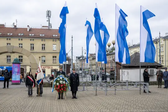 Uroczystość złożenia wieńca przy flagach, obecni przedstawiciele władz i mieszkańcy.