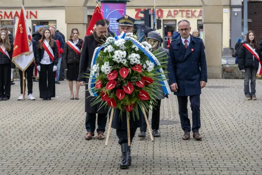 Uroczystość złożenia wieńca w hołdzie, uczestnicy w mundurach i z flagami.