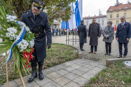 Uroczystość składania wieńca w towarzystwie flag i uczestników.
