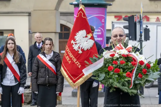 Uroczystość złożenia wieńca z flagą i przedstawicielami władz lokalnych.