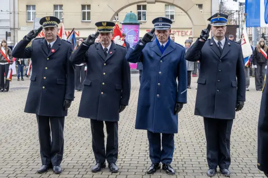 Czterech mężczyzn w mundurach salutuje podczas uroczystości.