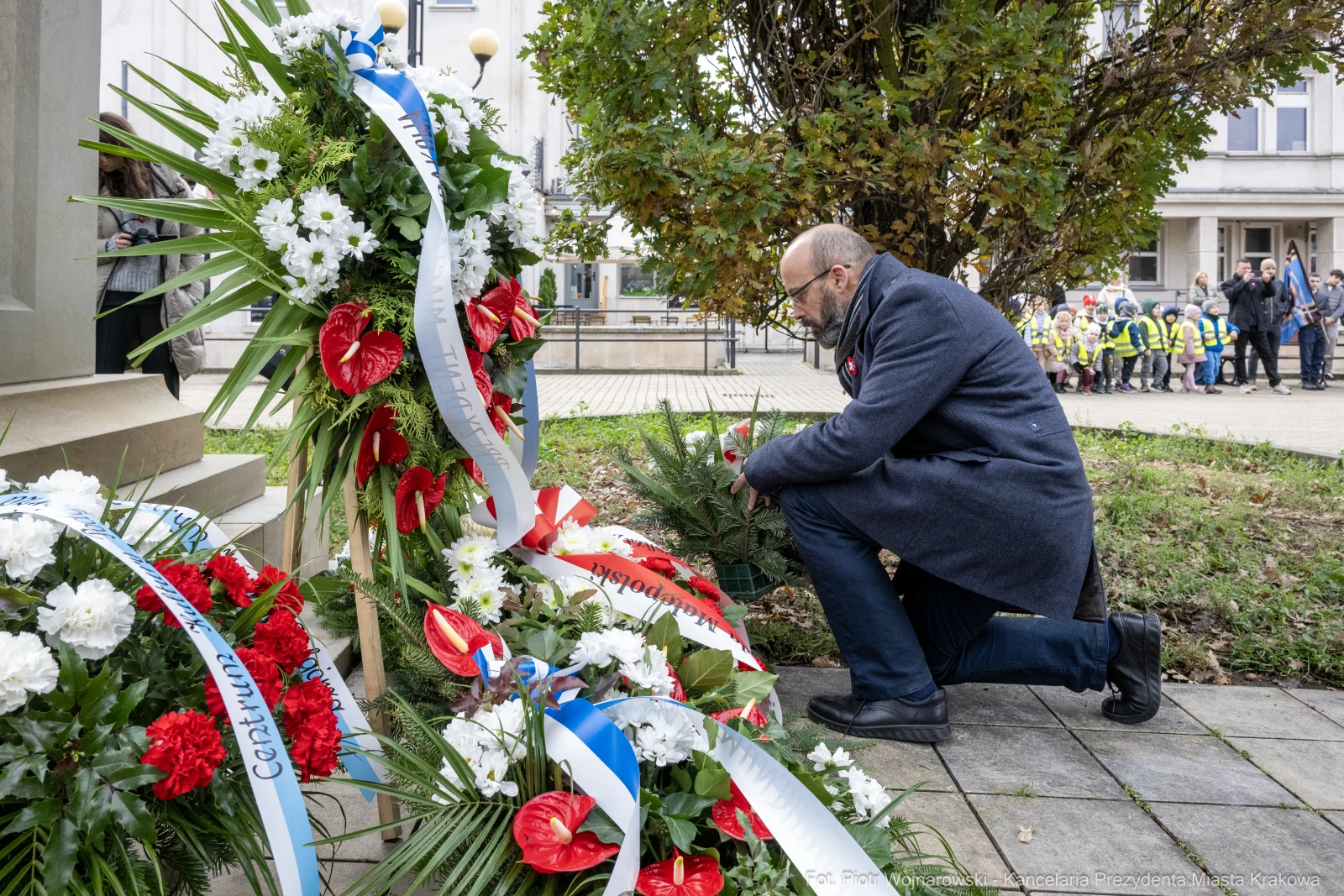 Mężczyzna klęczy przy kwiatach i zniczach, składając hołd.  Autor: Piotr Wojnarowski