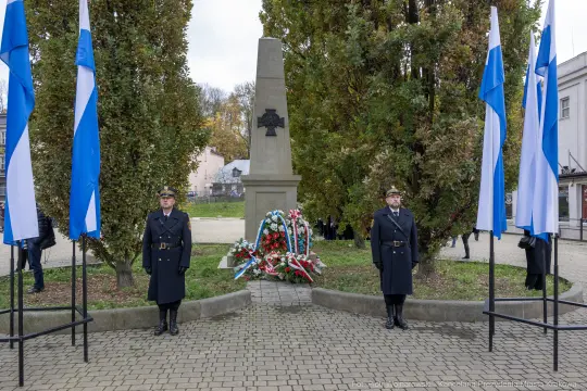 Pomnik z flagami i wartą honorową, złożone kwiaty w hołdzie.