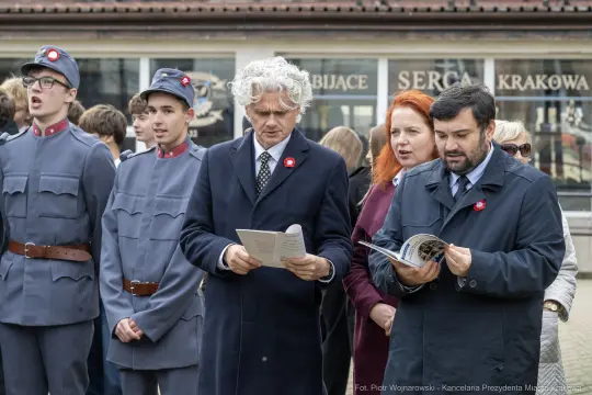 Uczestnicy uroczystości z okazji święta, w mundurach i z symbolami narodowymi.