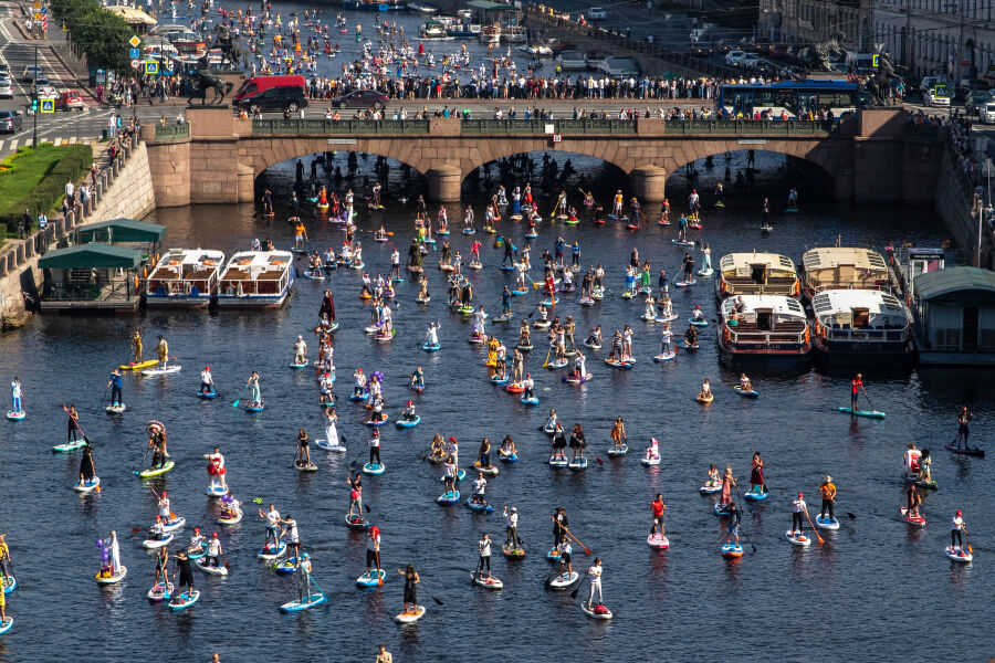 Widok z góry na kanał wodny przy ul. Fontanka w St. Petersburgu po którym na deskach do sup-surfingu płyną zawodnicy i uczestnicy festiwalu