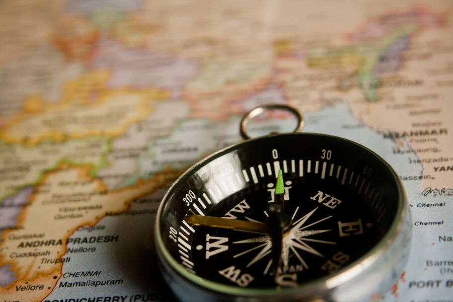 W powiększeniu zdjęcie kompasu leżącego na mapie świata