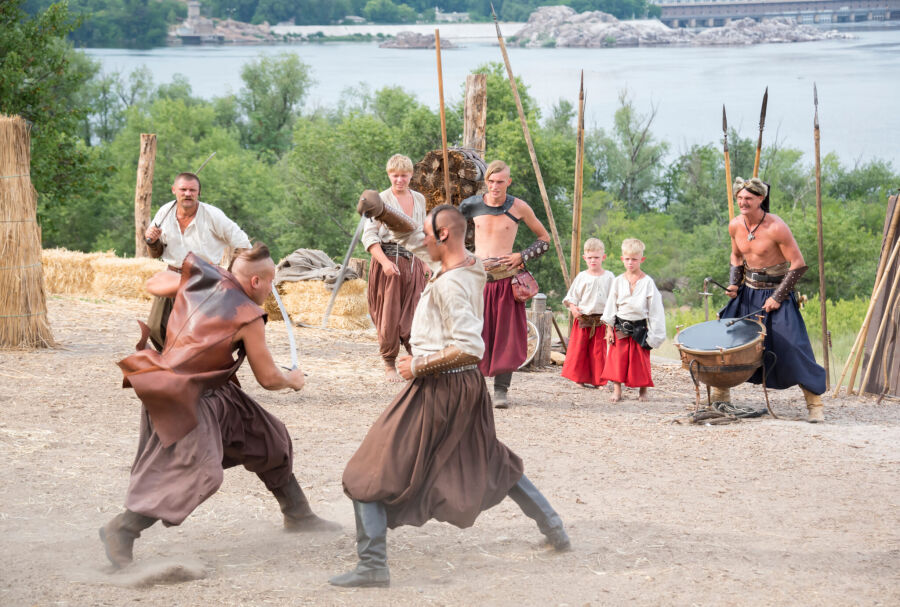 Inscenizacja walki historycznej. Kozacy z Zaporoża ubrani w narodowe stroje Ukrainy - wyszywane koszule (soroczka), spodnie szarawary, wysokie buty. Charakterystyczne włosy i długie wąsy. Kozacy walczą na miecze