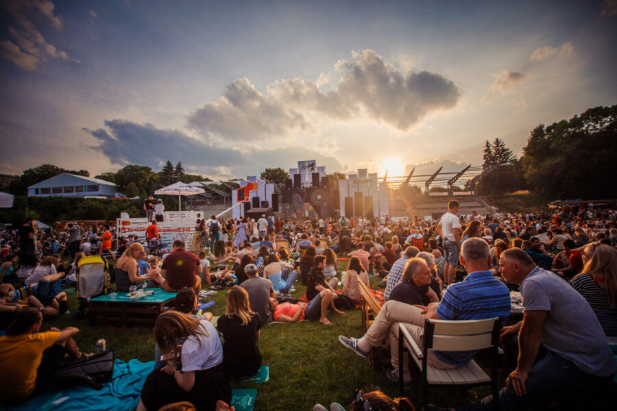 Przykładowe wydarzenie festiwalowe open-air we Lwowie. Scena festiwalowa, ludzie odpoczywają na krzesłach i leżakach, piknikują na łące miejskiej