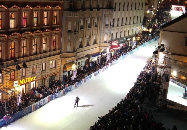 Slalom legend narciarskich na ulicach Zagrzebia widoczny z lotu ptaka narciarz jadący po śniegu do mety torem wytyczonym ulicą miasta. Po zmroku.  
