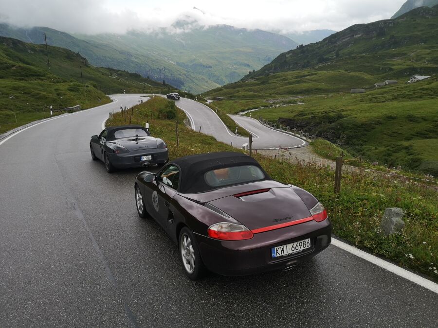 samochody marki Porsche na krętej asfaltowej drodze w górach