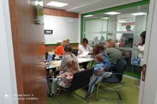 TZU CHI CHARITY FOUNDATION przekazała pomoc dla uchodźców z Ukrainy Osoby siedzą przy biurkach, obok podchodzą uchodźcy