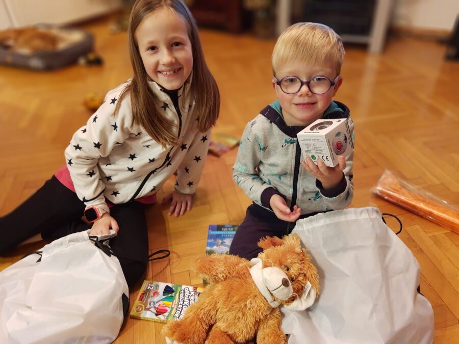 Zdjęcie przedstawia dwójkę dzieci rozpakowujących przezenty