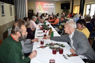 Spotkanie świąteczne 22.12.2022 r. Na fotografiach widać mieszkańców i pracowników Domu Pomocy Społecznej przy świątecznie nakrytych stołach
