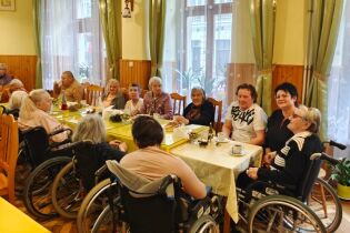 Spotkanie wigilijne Dyrektor Domu siedzi przy stole z Mieszkańcami