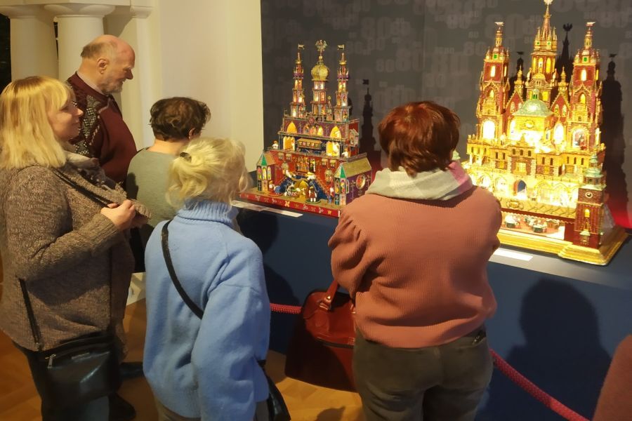Grupa osób ogląda dwie szopki krakowskie w sali muzeum