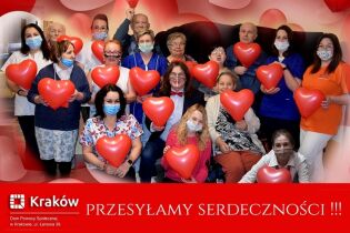 Serdeczny Dzień 15.02.2021 Zdjęcie przedstawia uśmiechniętą grupę Mieszkańców oraz personel w maskach higienicznych. Wszyscy w rękach trzymają czerwone balony w kształcie serca.