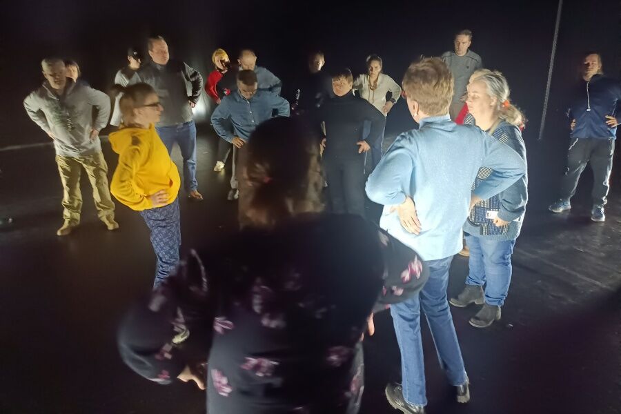 Uczestnicy stoją na scenie wspierając ręce na biodrach.