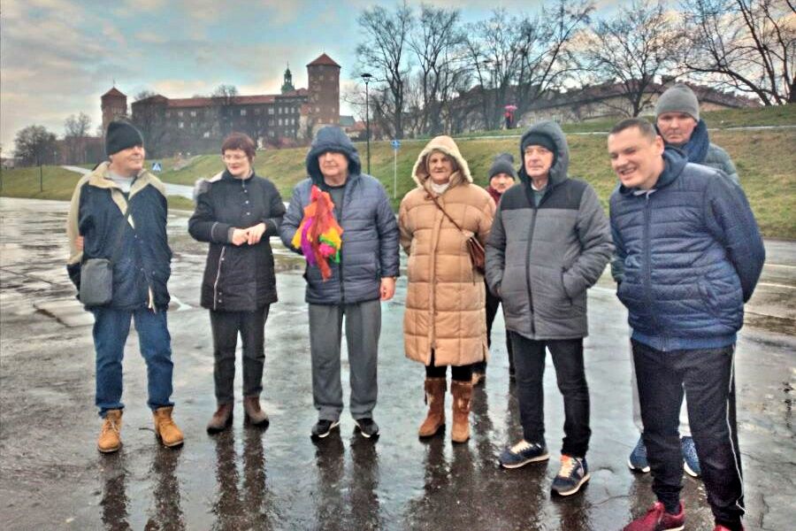 Grupa dwóch kobiet i sześciu mężczyzn nad Wisłą. Jeden z mężczyzn trzyma w ręku marzannę.