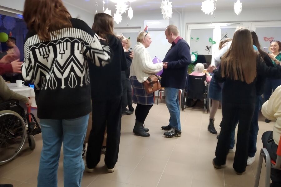 Grupa kobiet i mężczyzn tańczących w pomieszczeniu.