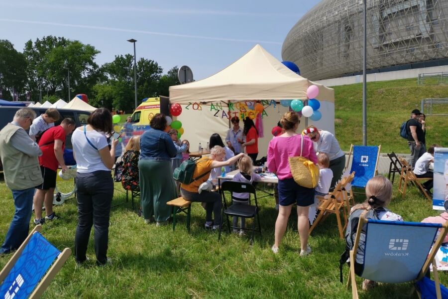 Rodziny uczestniczące w zabawach plenerowych, częściowo odbywających się w namiocie. 